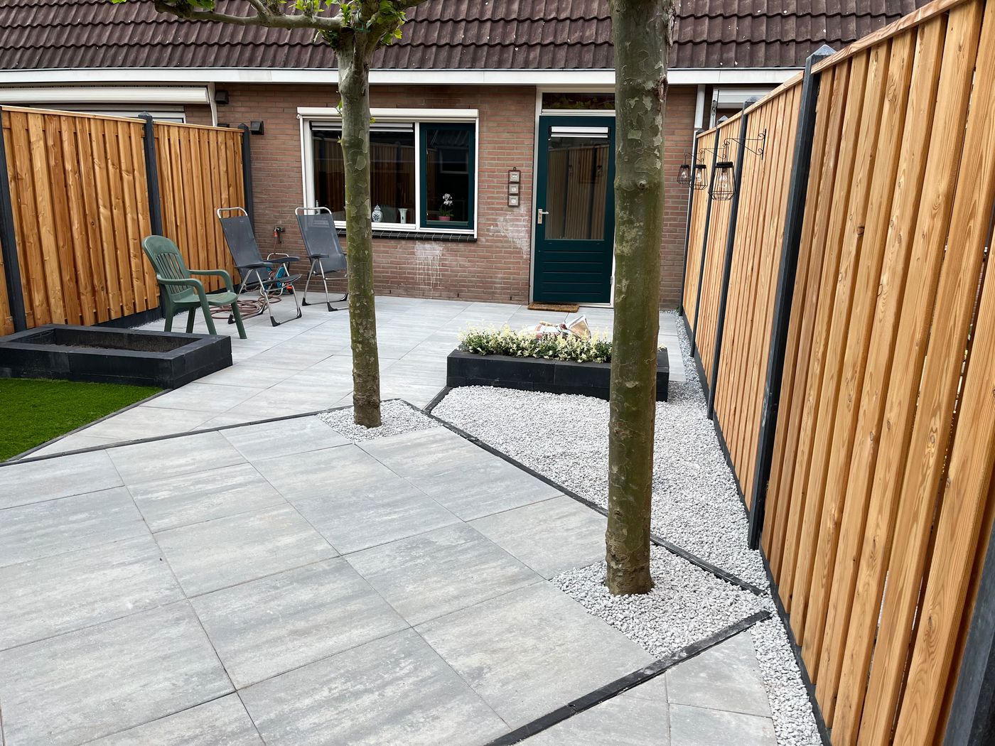 Achtertuin met keramische tegels, houten schutting en kunstgras