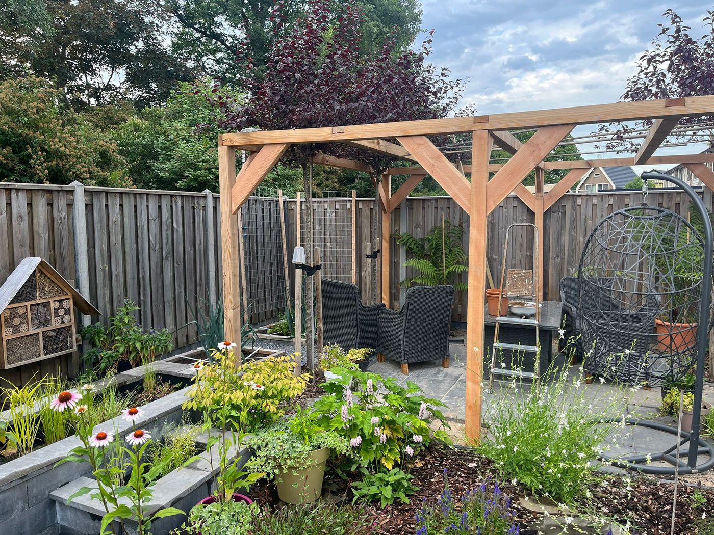 Houten pergola met loungehoek tussen borders